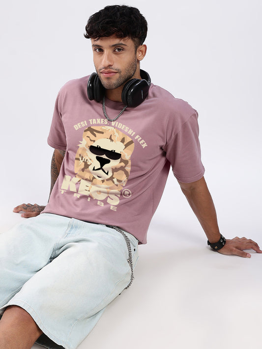 Man wearing a pink t-shirt with a graphic design, sitting on a white surface.