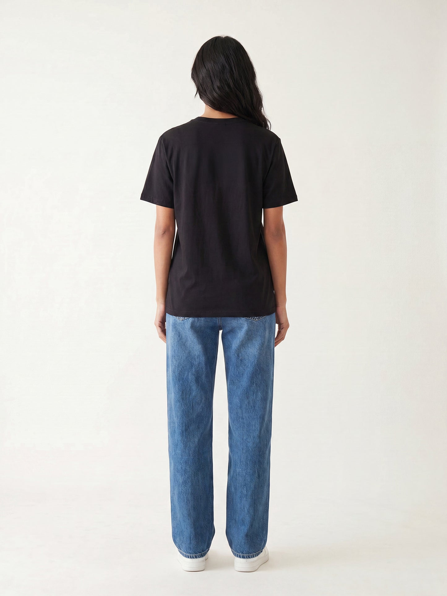 Back view of black Keos cotton t-shirt styled with blue denim jeans, showing clean regular fit and minimal everyday styling.