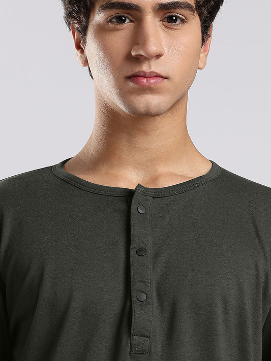 Man wearing a dark green henley shirt against a plain background
