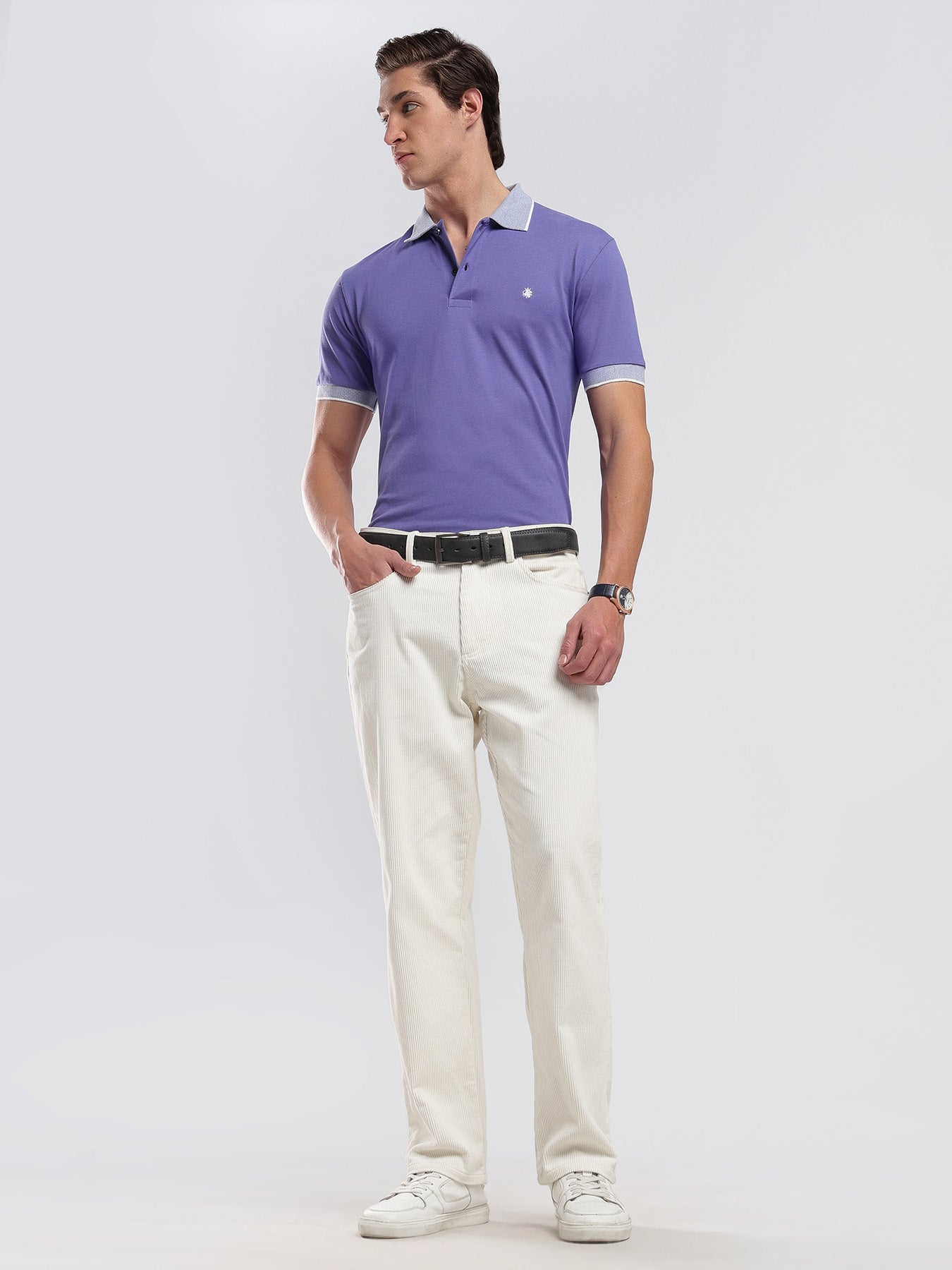 Man wearing a purple polo shirt and white pants on a plain background