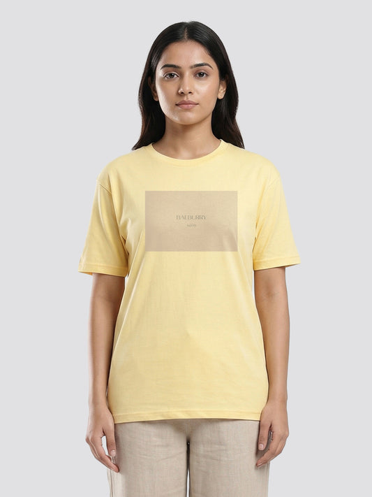 Woman wearing a yellow t-shirt with a beige square design on a light gray background