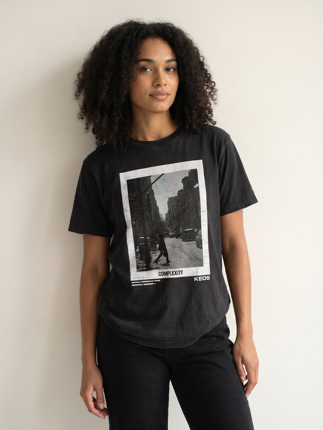 Person wearing a black t-shirt with a graphic design on a plain background