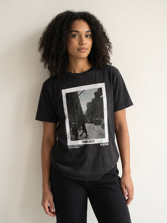 Person wearing a black t-shirt with a graphic design on a plain background