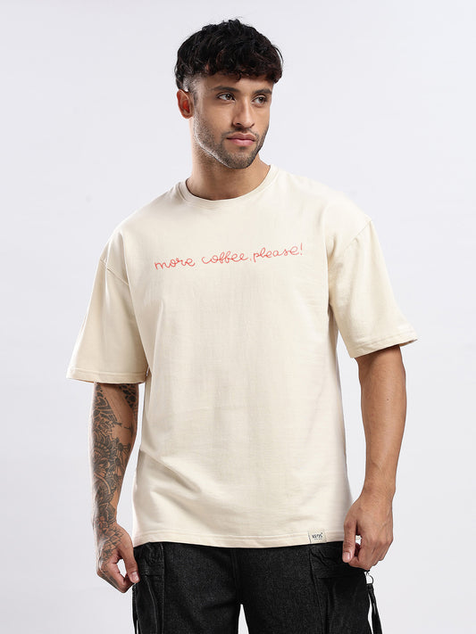 Man wearing a beige t-shirt with 'more coffee please!' text on a white background