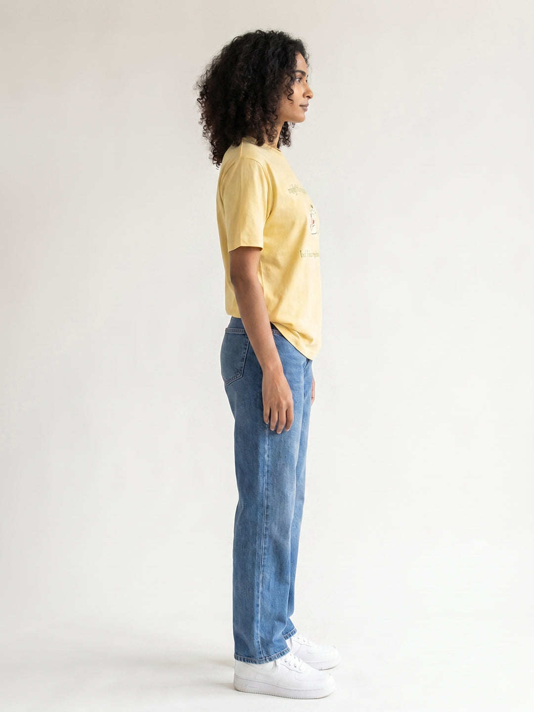Person wearing a yellow t-shirt and blue jeans standing against a white background