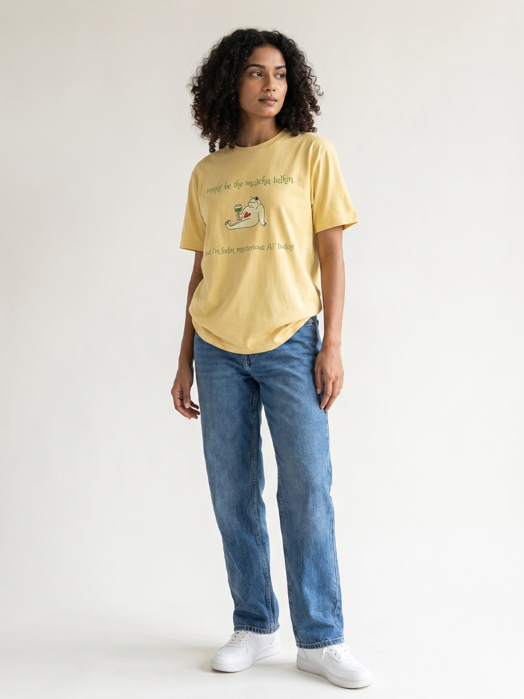 Woman wearing a yellow t-shirt and blue jeans on a white background