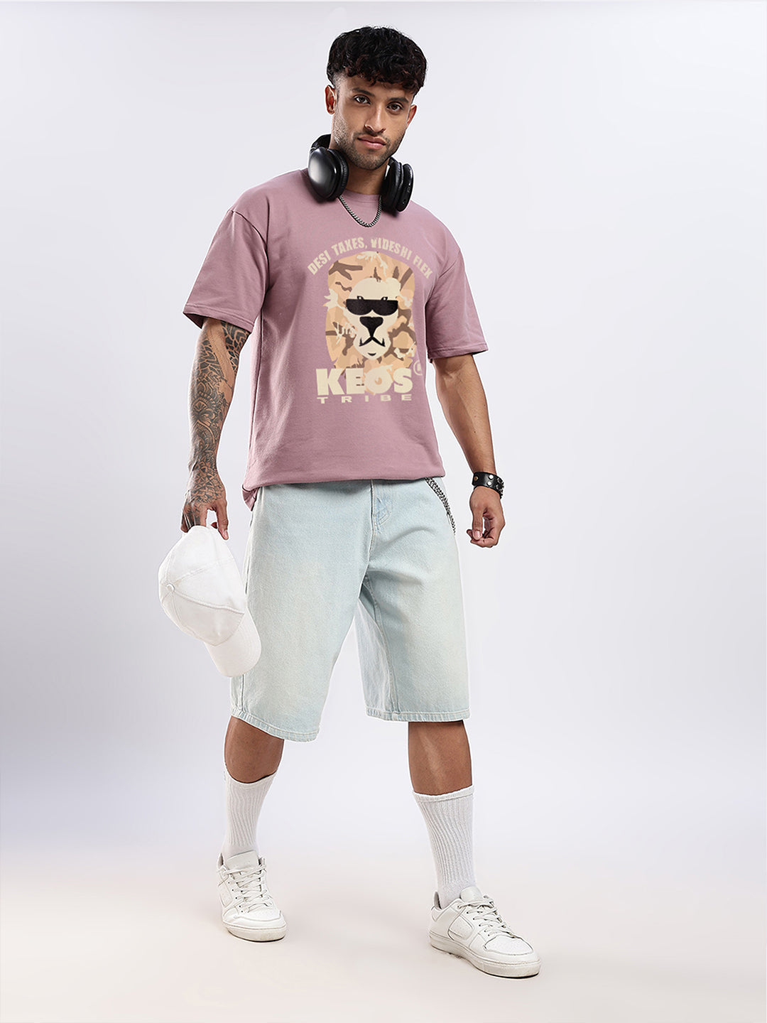 Man wearing a pink t-shirt with a graphic design and light blue shorts on a white background
