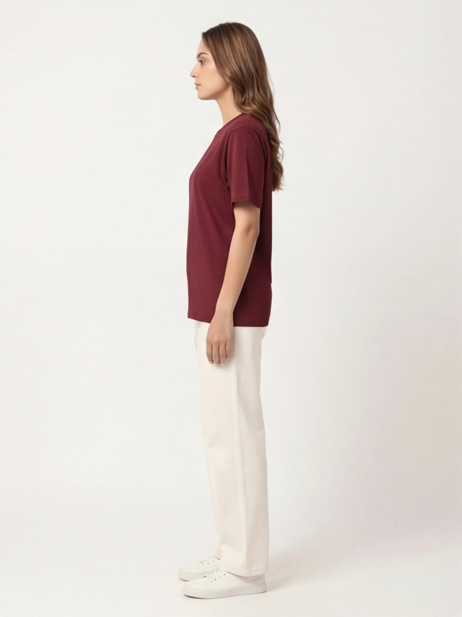 Person wearing a burgundy top and white pants on a white background