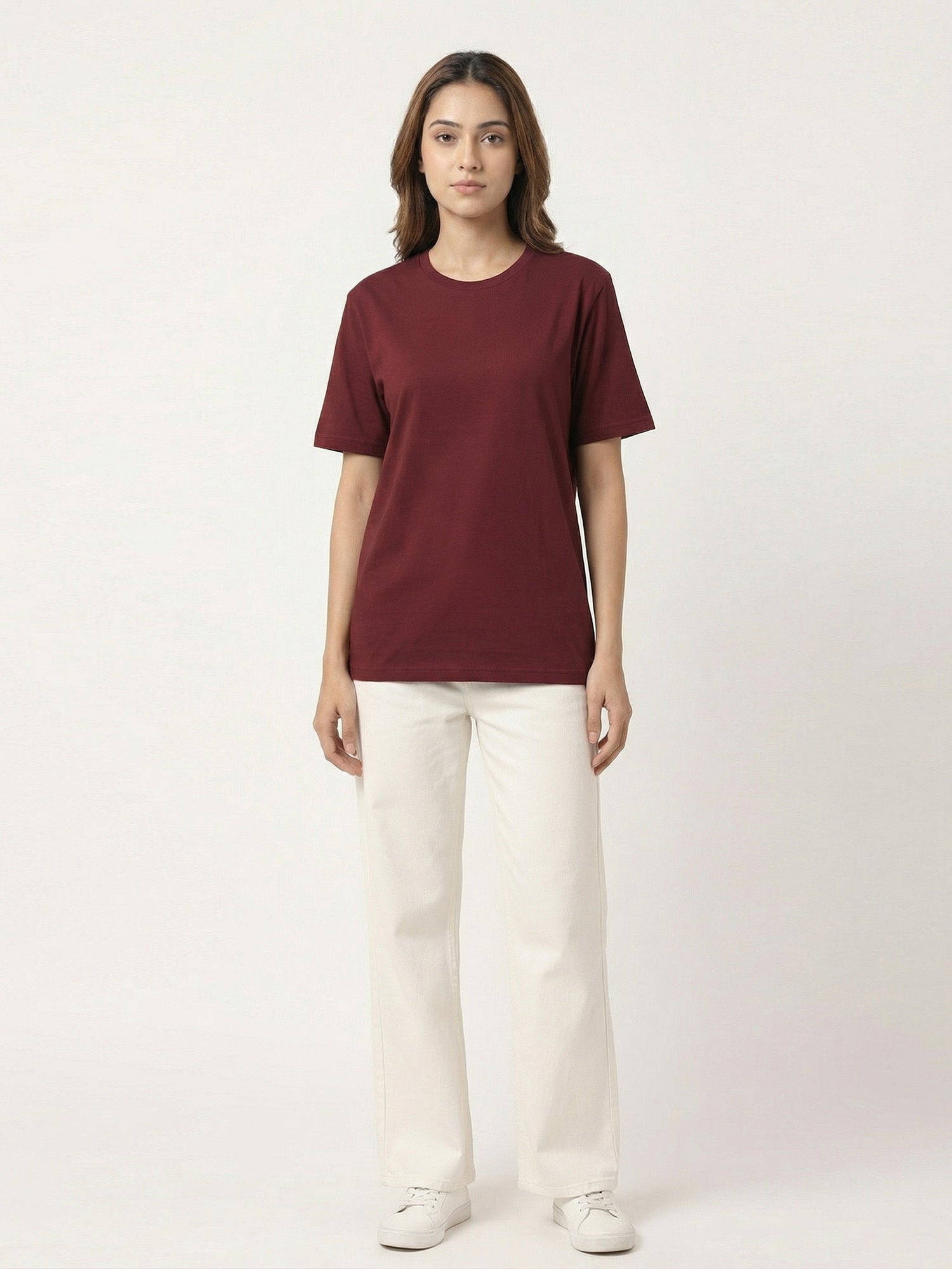 Person wearing a maroon t-shirt and white pants on a white background