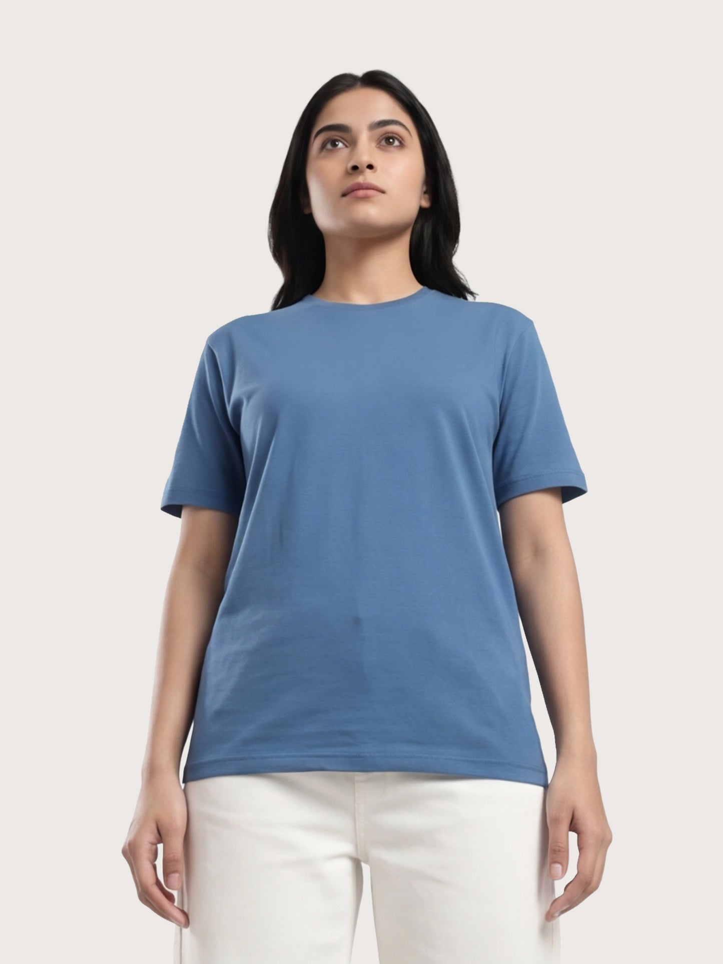 Woman wearing a blue t-shirt and white pants on a light gray background