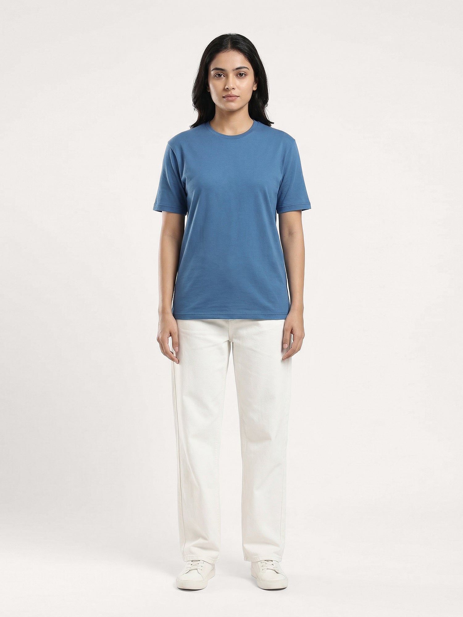 Person wearing a blue t-shirt and white pants on a white background