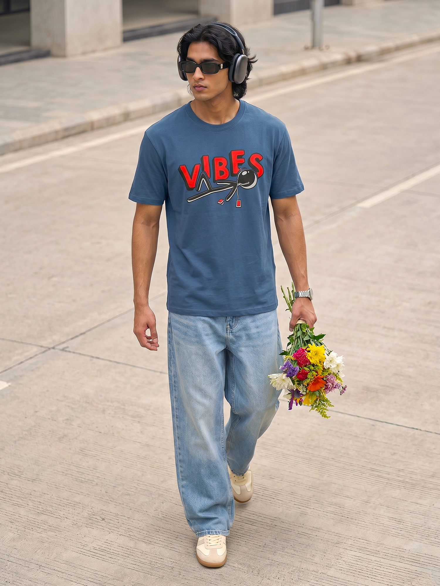 Blue Vibes Graphic T-Shirt Keos blue graphic t-shirt paired with relaxed light wash denim and white sneakers. A modern streetwear look featuring headphones, fresh flowers and effortless city style, blending music culture, casual fashion and youthful self-expression.
