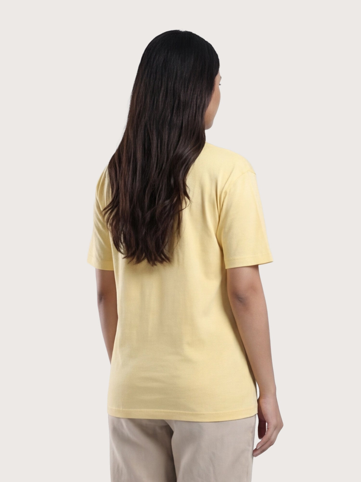 Woman wearing a yellow t-shirt on a plain background