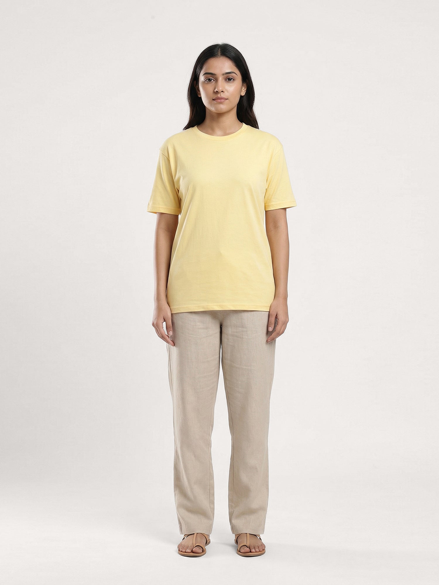 Woman wearing a yellow t-shirt and beige pants on a white background