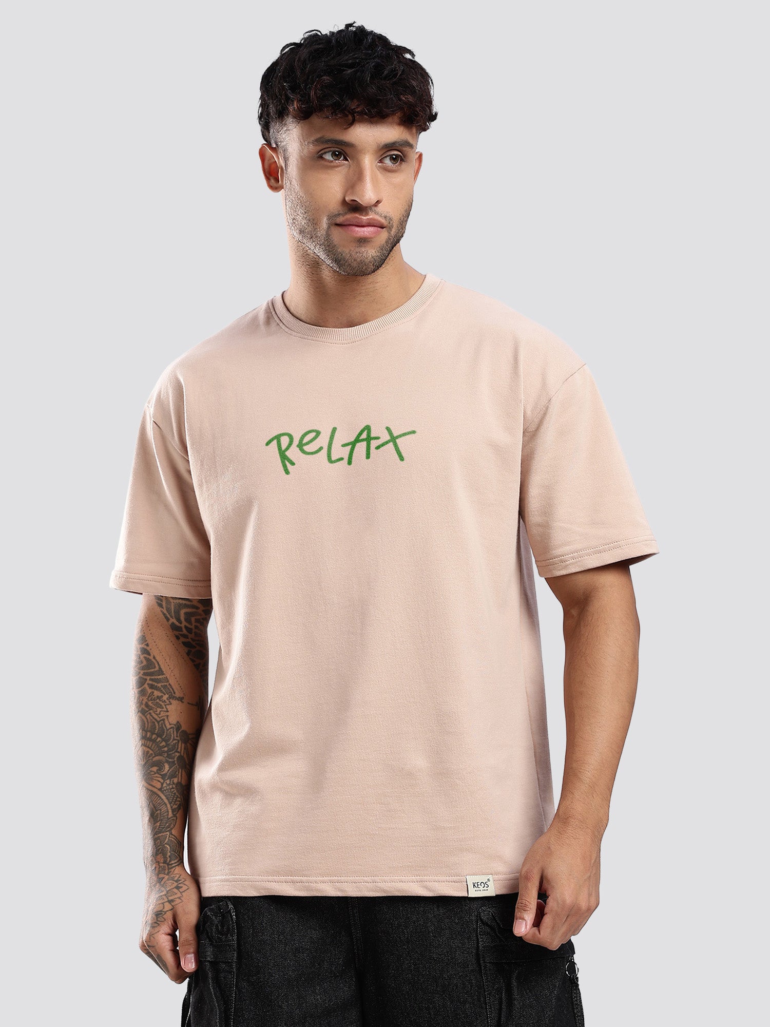 Man wearing a beige t-shirt with 'RELAX' in green text on a plain background