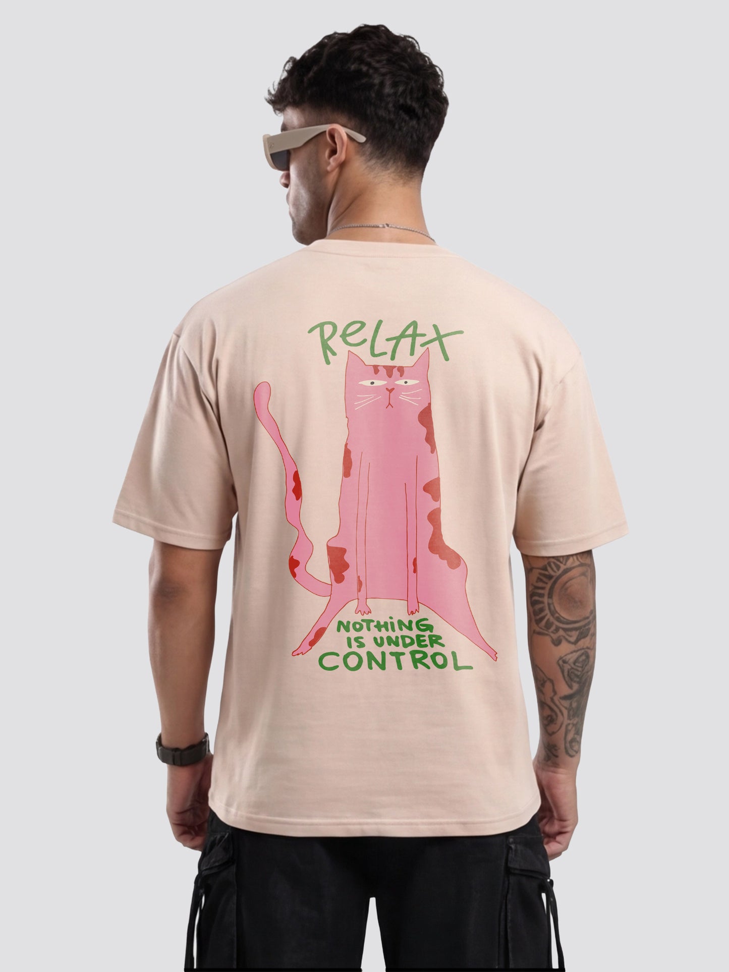 Person wearing a beige t-shirt with a pink cat graphic and text on the back, on a white background