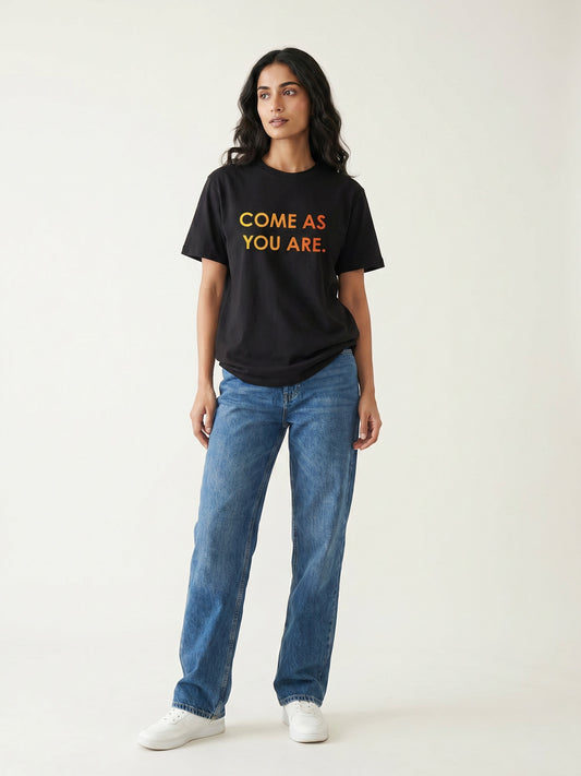 Keos Come As You Are black cotton graphic t-shirt for women, featuring bold Pride Month statement text with blue jeans and white sneakers.