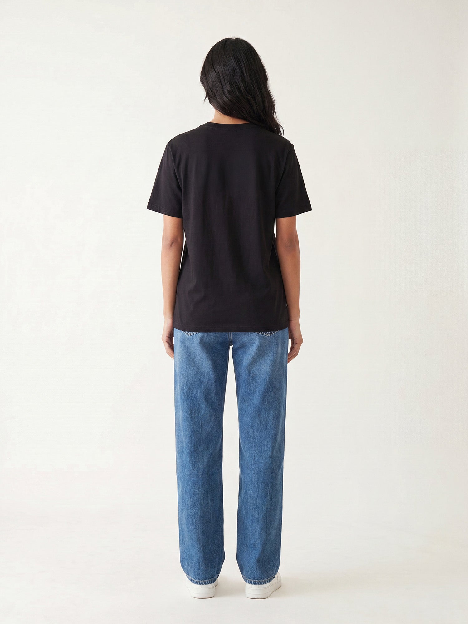 Back view of black Keos cotton t-shirt styled with blue denim jeans, showing clean regular fit and minimal everyday styling.