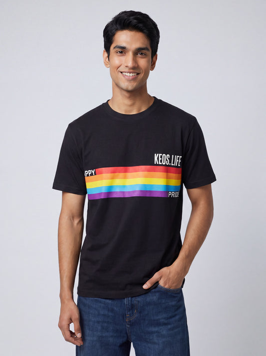 Indian male model wearing Keos Happy Pride black graphic t-shirt with rainbow stripe print, styled with blue denim jeans.