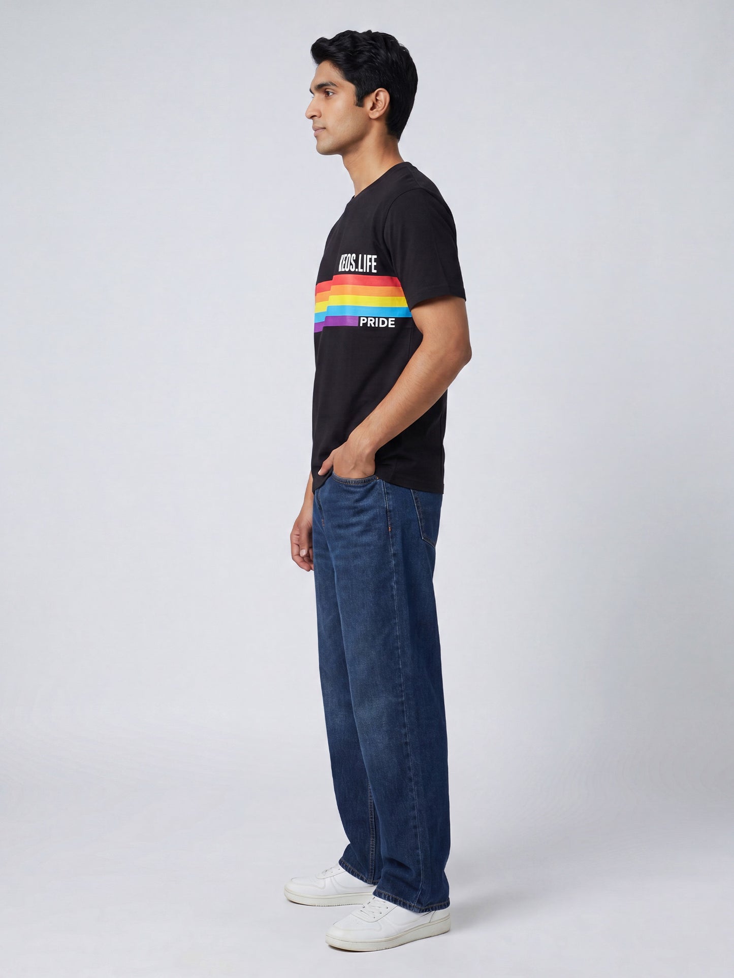Side profile of men’s black Keos Happy Pride graphic tee with colourful rainbow chest print, styled with relaxed blue jeans.