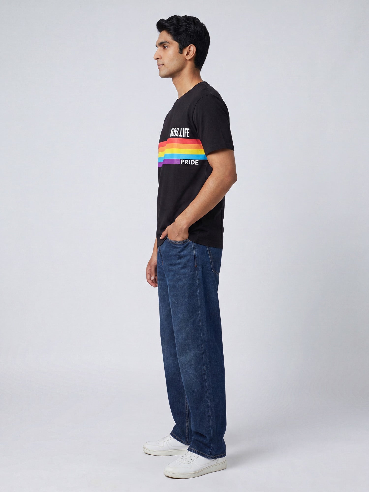 Side profile of men’s black Keos Happy Pride graphic tee with colourful rainbow chest print, styled with relaxed blue jeans.