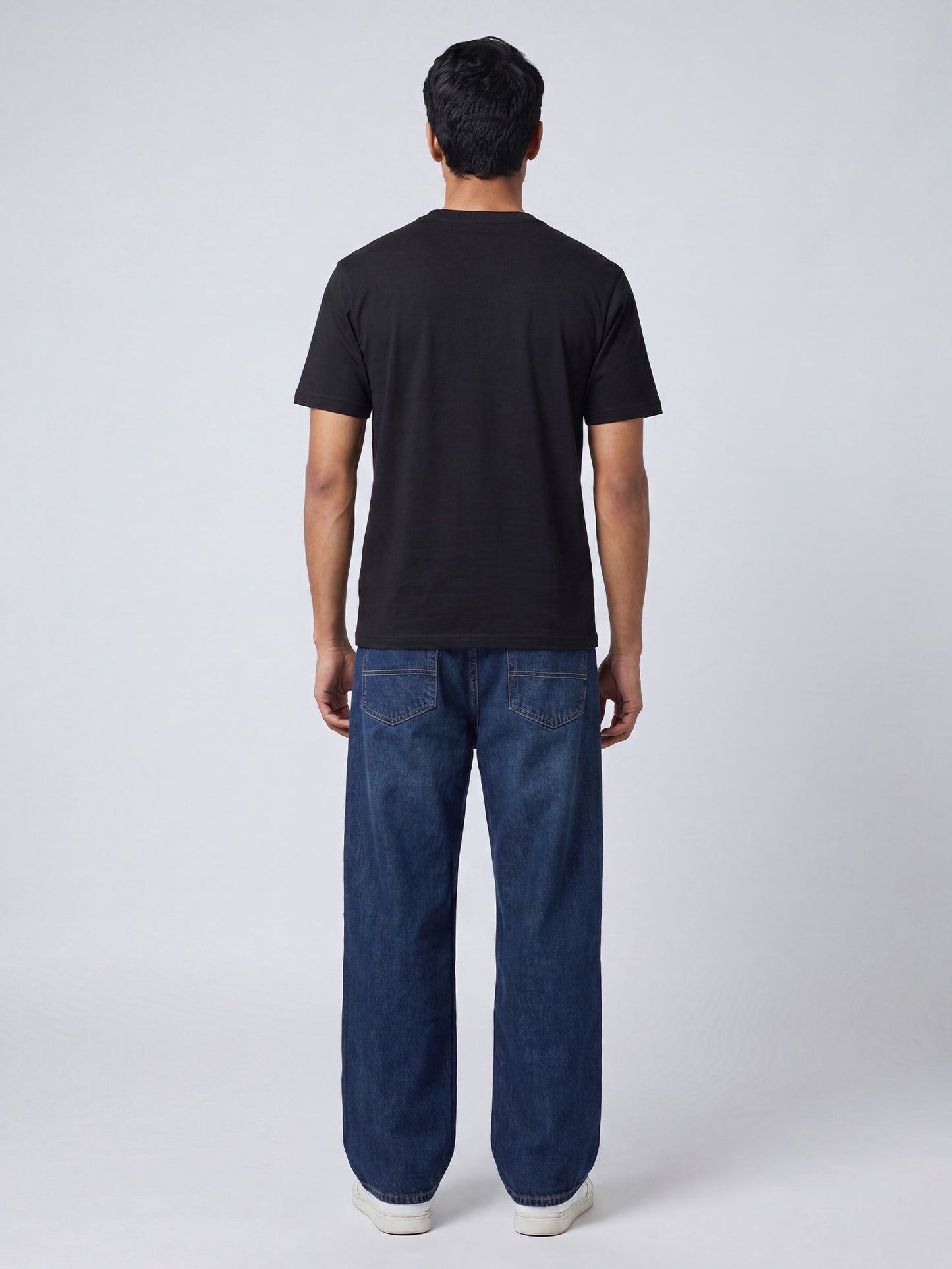 Back view of black Keos cotton t-shirt styled with blue denim jeans, showing clean regular fit and minimal everyday styling.