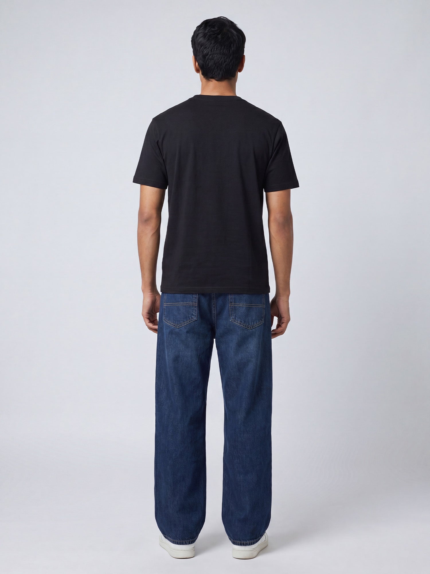 Back view of black Keos cotton t-shirt styled with blue denim jeans, showing clean regular fit and minimal everyday styling.