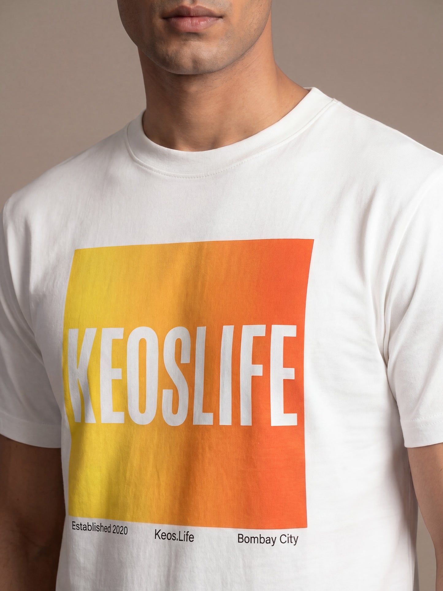 Close-up of Keos Pride Block white cotton t-shirt showing yellow orange KEOSLIFE graphic print, crew neck, and premium fabric texture.