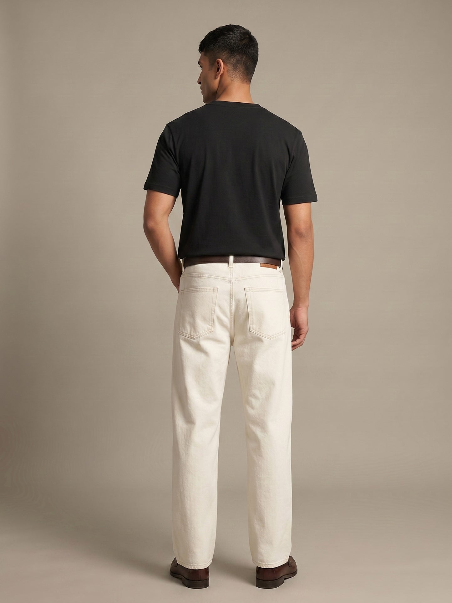 Back view of black Keos cotton t-shirt styled with off-white denim, showing clean regular fit and minimal everyday menswear styling.