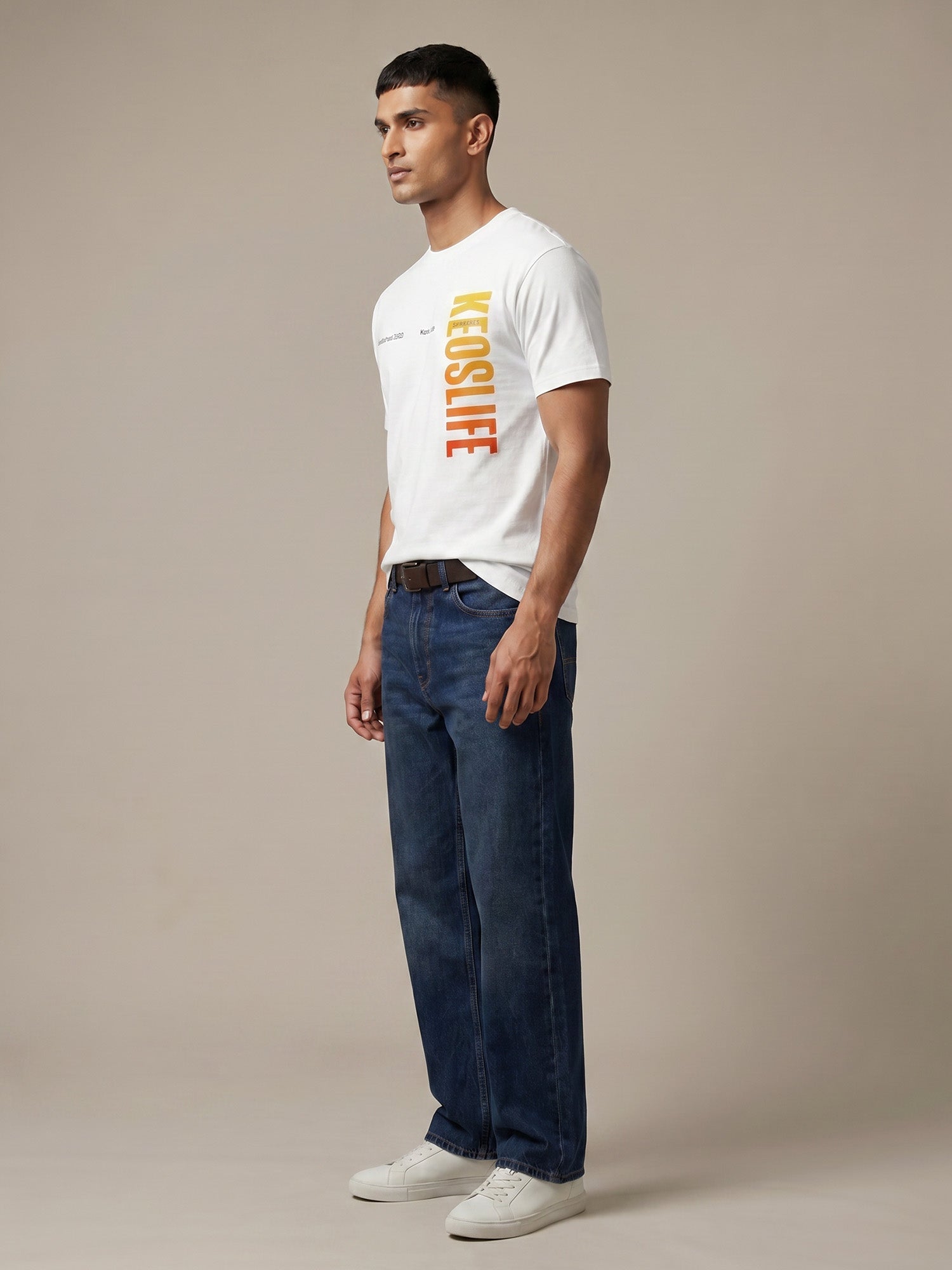 Side profile of men’s white Keos Pride Bold graphic tee with vertical yellow orange chest print, styled with straight-fit blue denim.