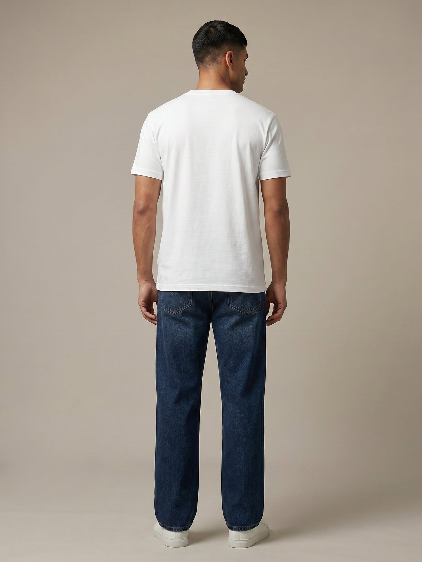 Back view of white Keos cotton t-shirt styled with blue denim jeans, showing clean regular fit and minimal everyday menswear styling.