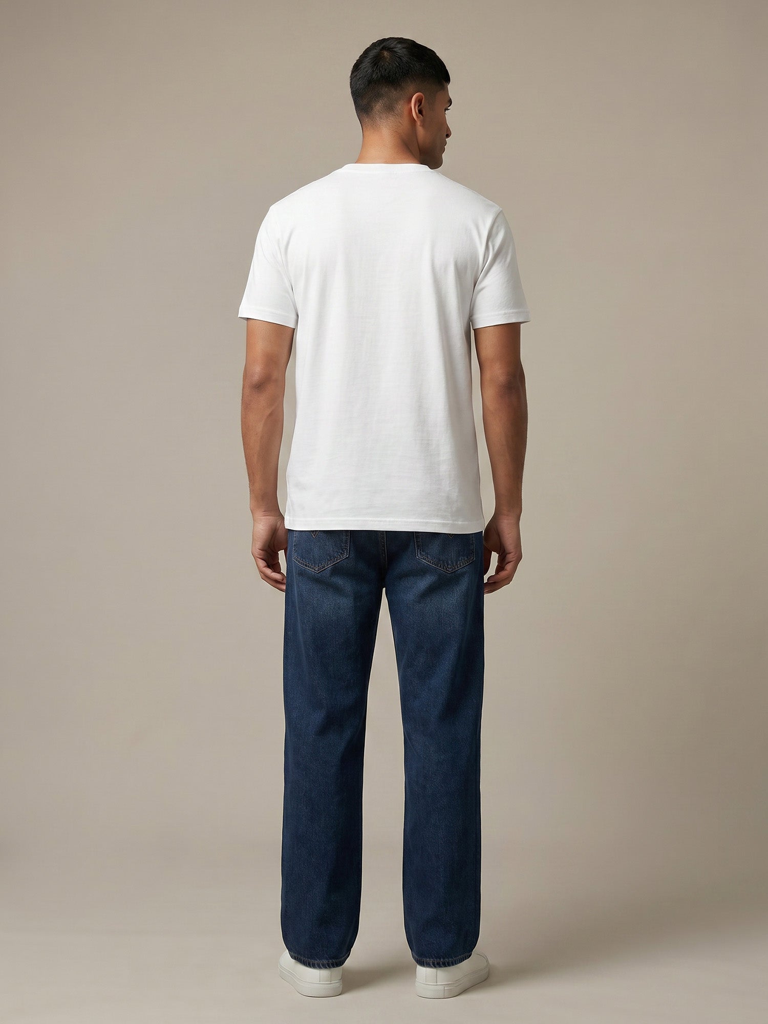 Back view of white Keos cotton t-shirt styled with blue denim jeans, showing clean regular fit and minimal everyday menswear styling.