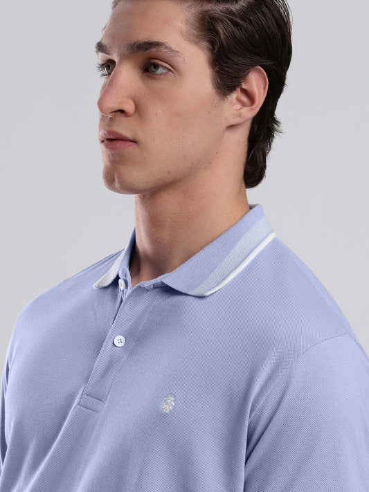 Man wearing a light blue keos polo shirt with white trim on a gray 