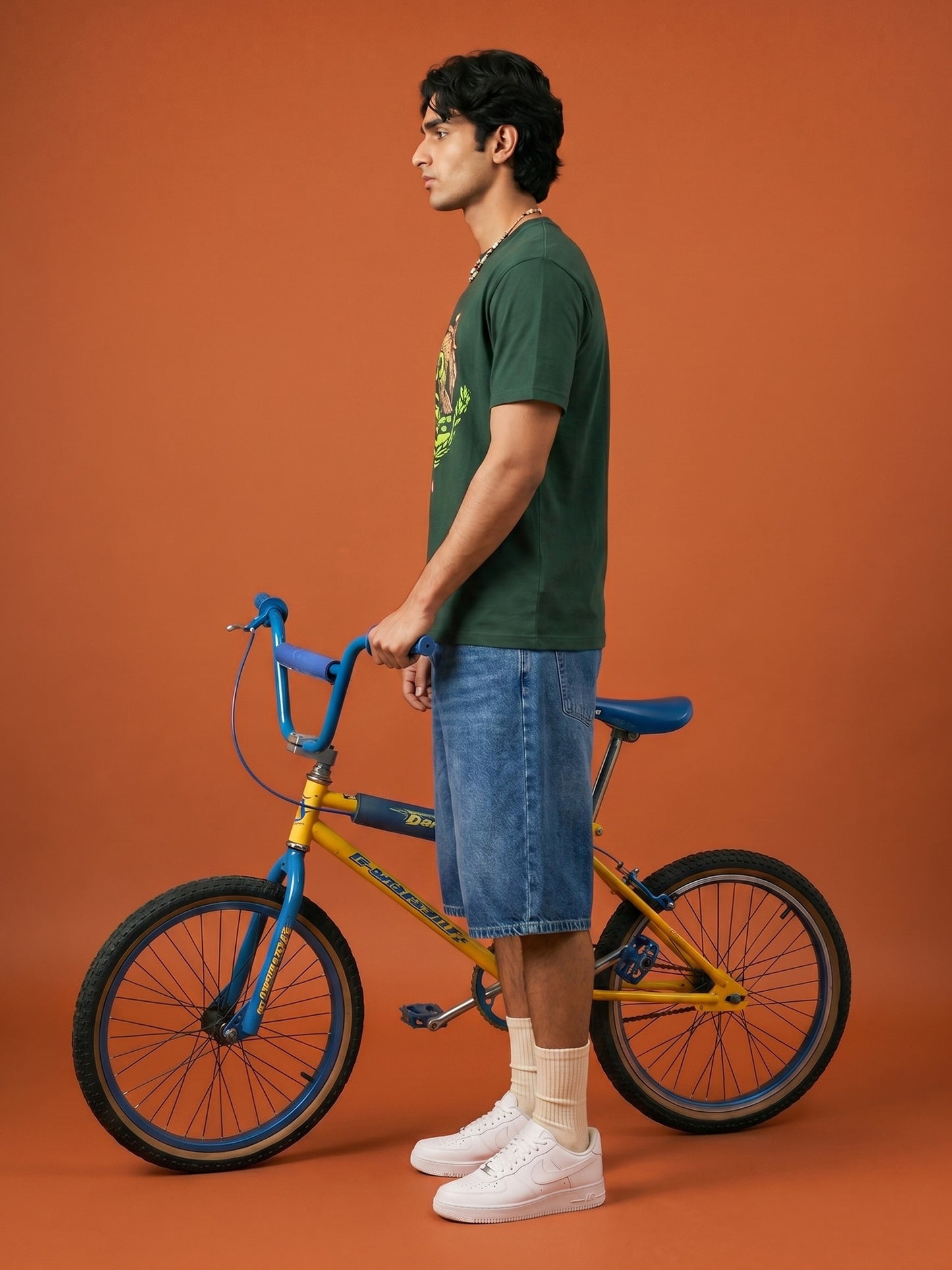 Man standing next to a yellow bicycle on an orange background