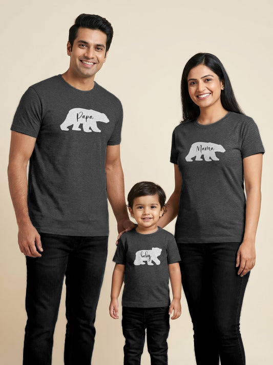 Family of three wearing matching dark gray t-shirts with bear illustrations and text on a beige background