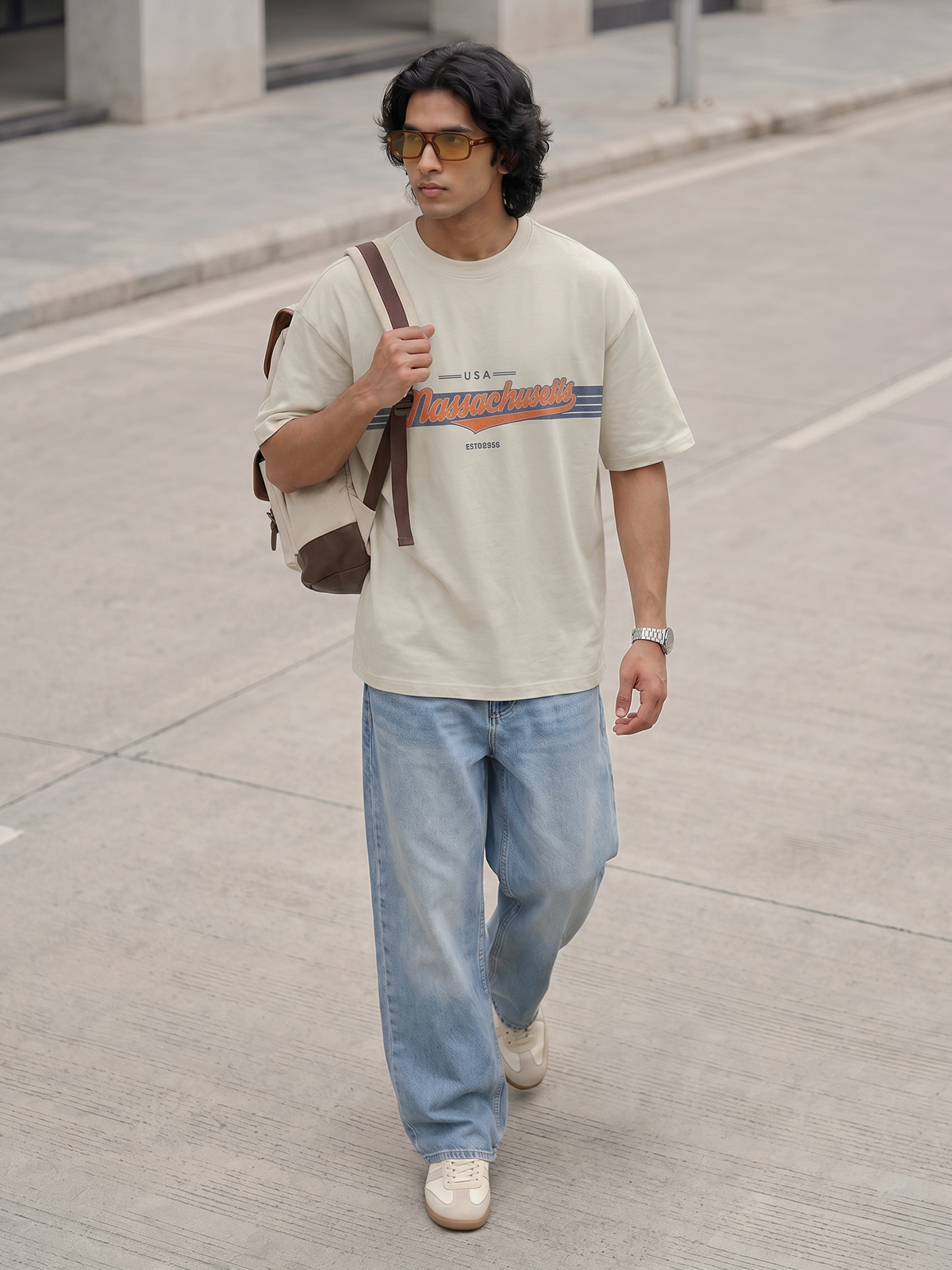 Off-White Graphic T-Shirt Keos men’s oversized graphic t-shirt with retro typography print paired with relaxed-fit denim jeans and sneakers. Modern streetwear outfit inspired by vintage Americana fashion, oversized clothing, casual everyday wear and contemporary urban style.
