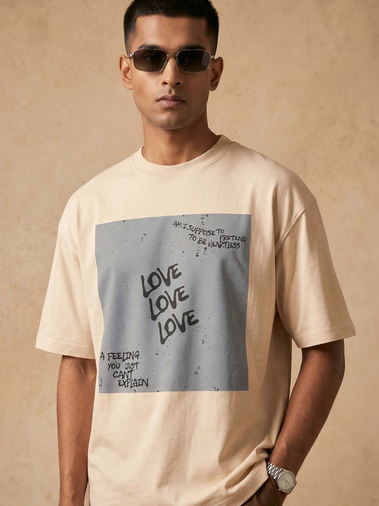 Man wearing a beige t-shirt with a graphic design on a beige background