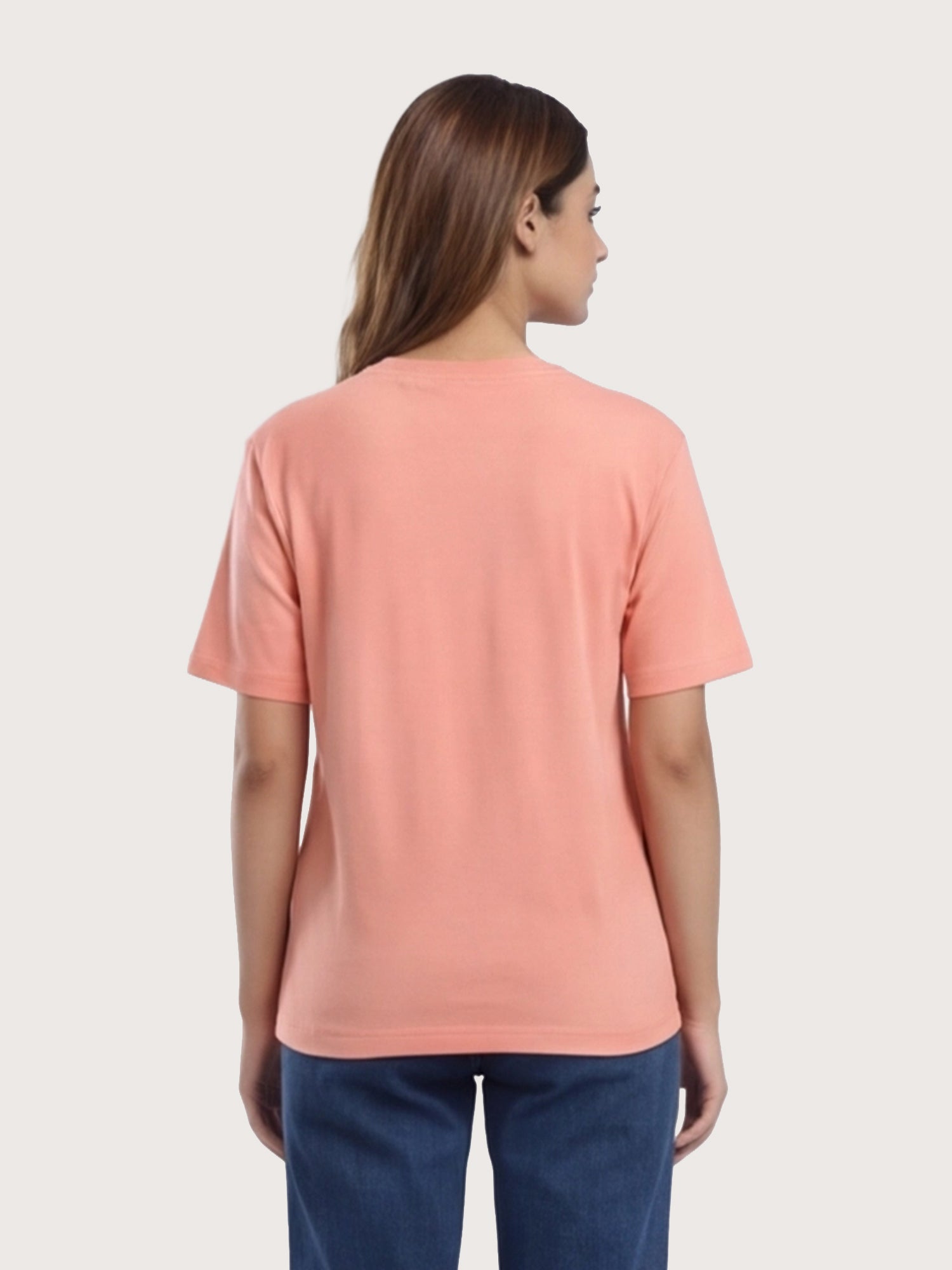 Woman wearing a peach-colored t-shirt on a plain background