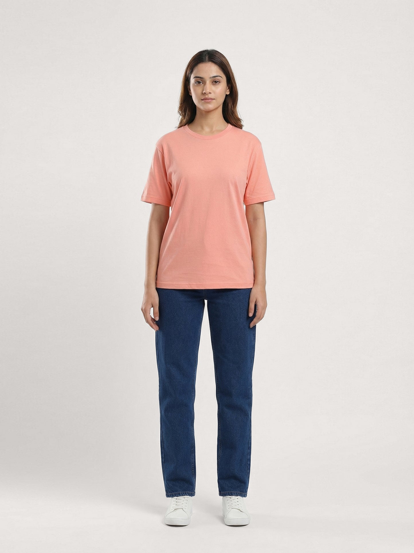 Person wearing a pink t-shirt and blue jeans on a white background