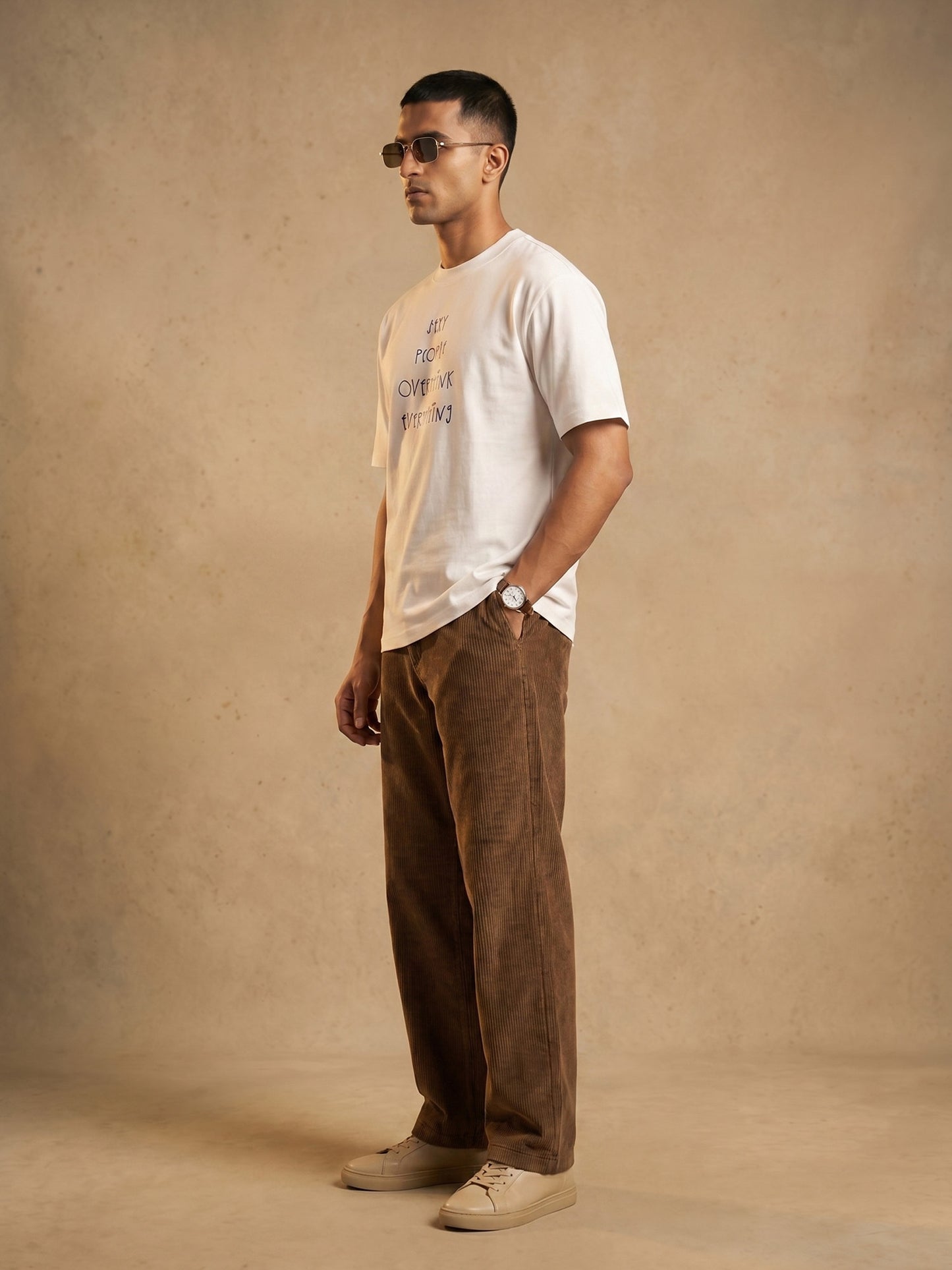 Side profile of men’s Keos Sexy People white graphic tee in regular fit, styled with brown corduroy trousers and sunglasses.