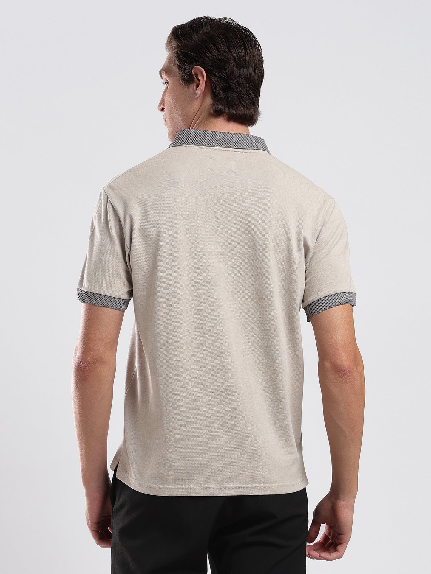 Man wearing a beige polo shirt with gray accents on a white background