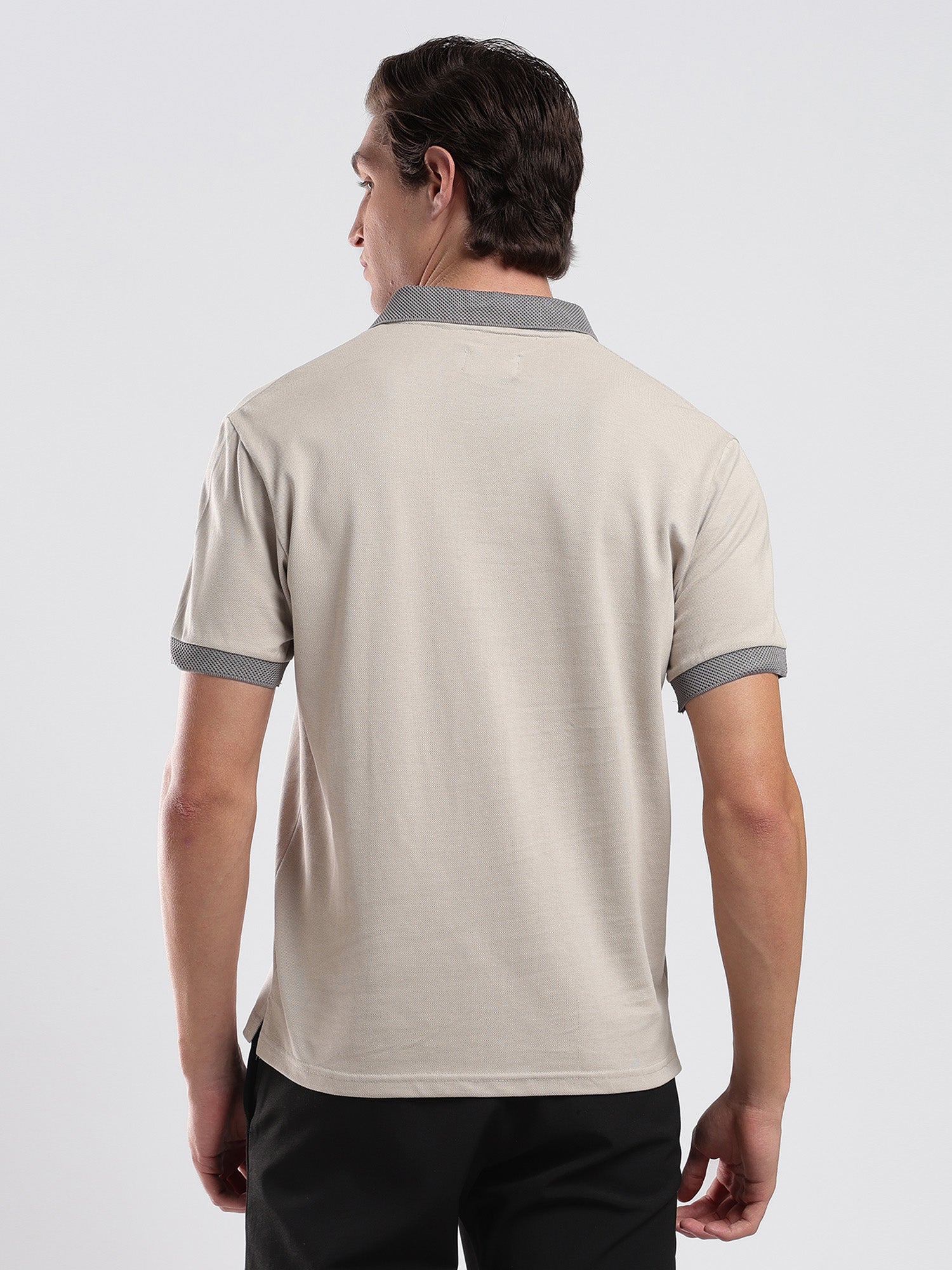Man wearing a beige polo shirt with gray accents on a white background