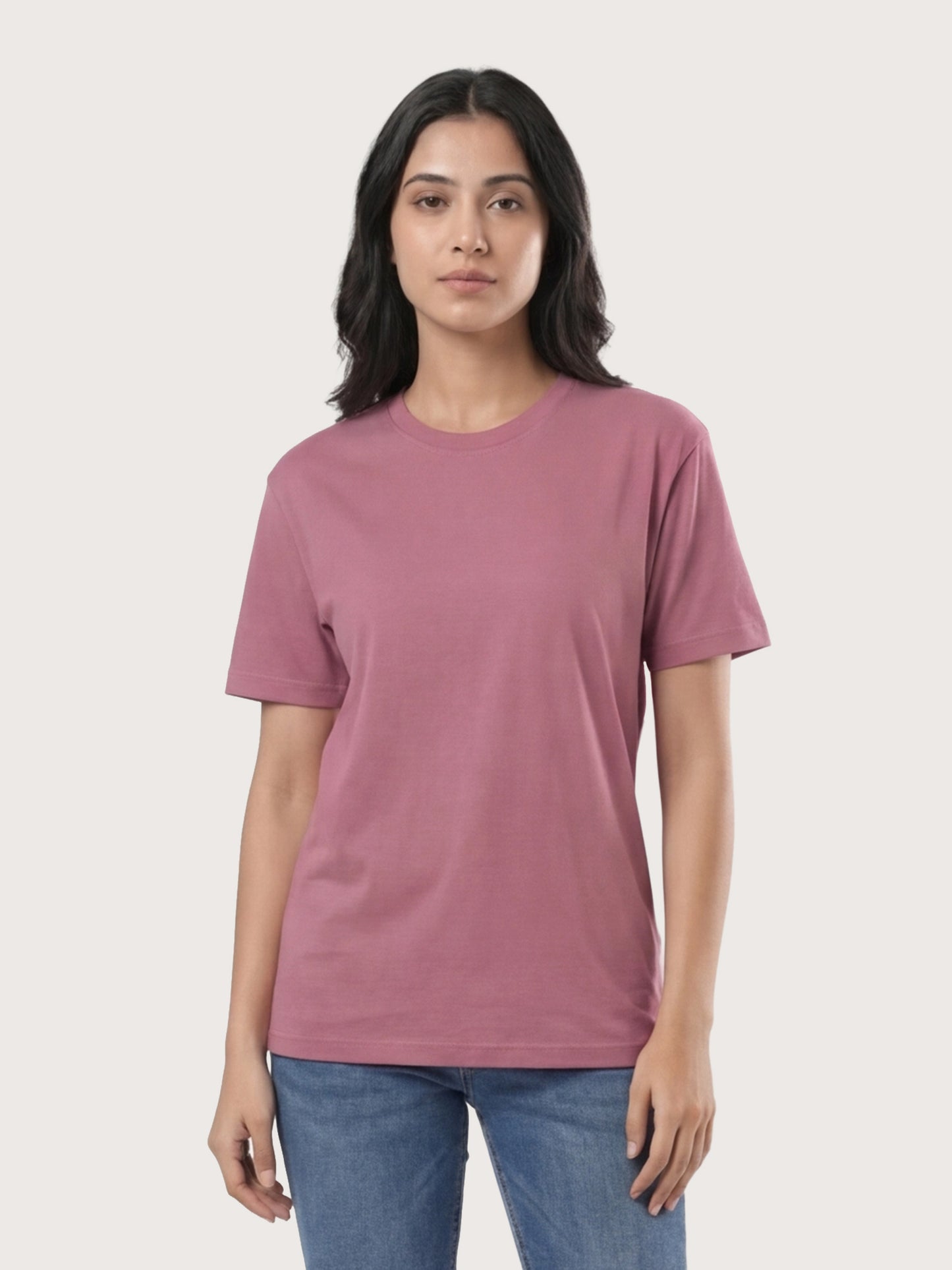 Person wearing a mauve t-shirt and blue jeans on a light gray background