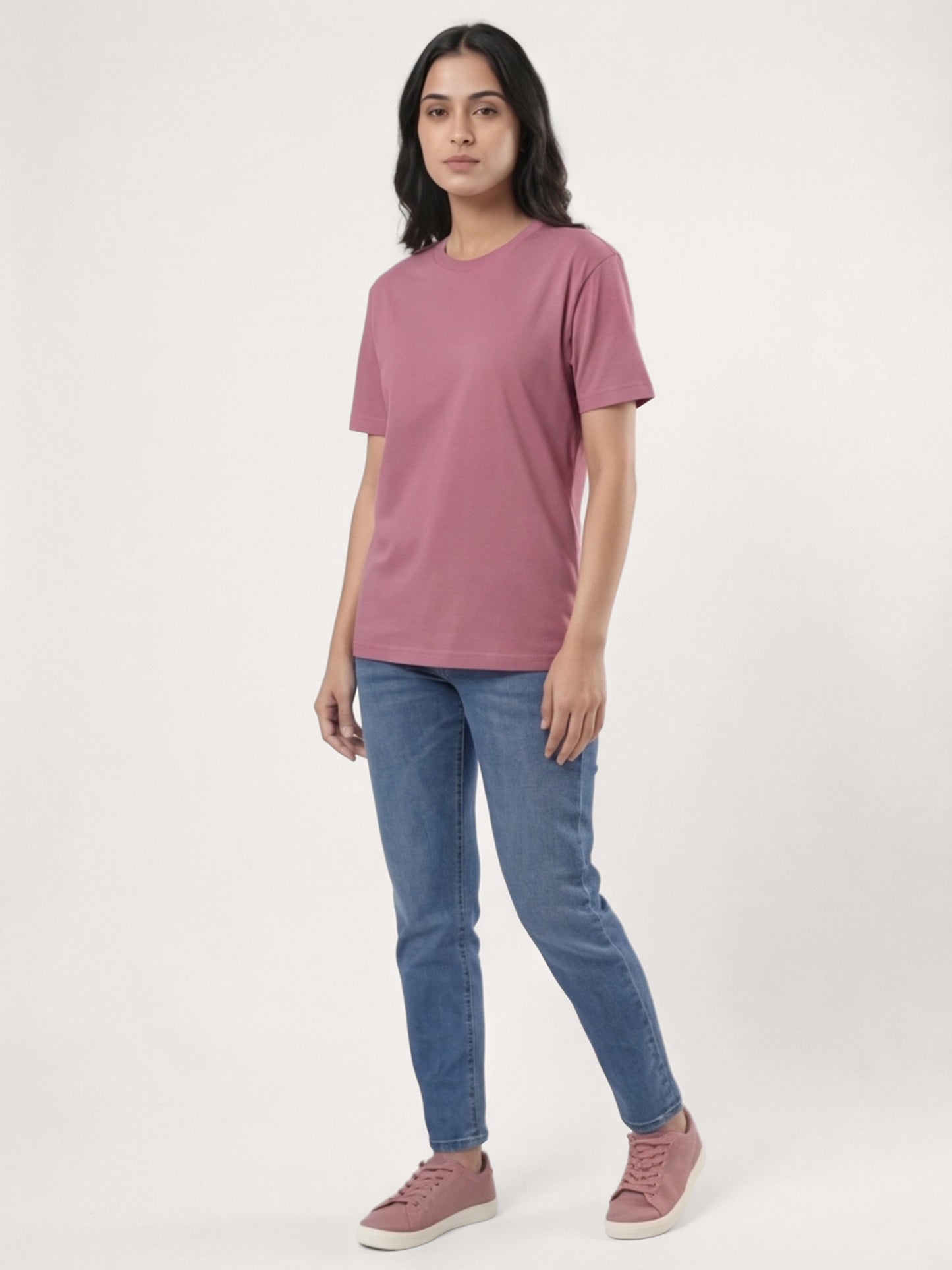 Woman wearing a pink t-shirt and blue jeans on a white background